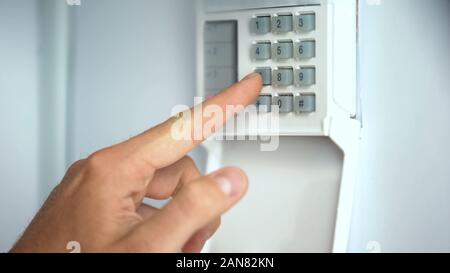 Man entering password on home security system, robbery protection, close up Stock Photo