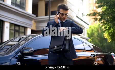 Real estate manager talking on phone and looking at watch, waiting for customers Stock Photo