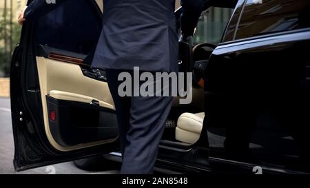 Businessman getting in luxurious car, driving to important meeting, millennial Stock Photo