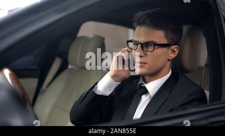 Upset politician talking on phone, sitting in car, business trip, travelling Stock Photo