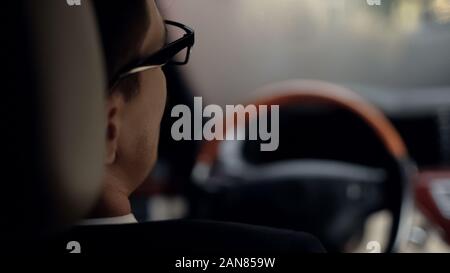 Back view of man in car waiting for client, premium class taxi driver, close up Stock Photo