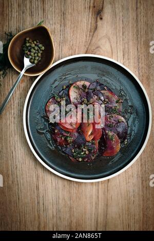 Healthy vegan food. Beetroot carpaccio appetiser with capers and dill dressing. Wooden Background Stock Photo