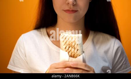 Woman holding shawarma, cheap delicious but unhealthy food, addiction Stock Photo