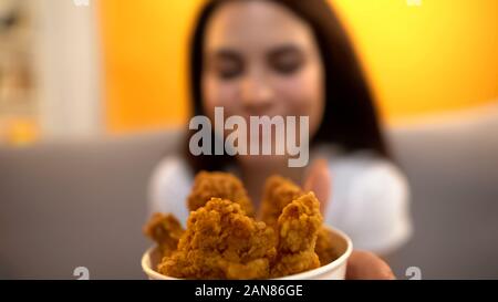 Smiling lady smelling appetizing roasted chicken legs at fast food restaurant Stock Photo