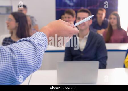 Cropped image of senior university professor pointing on something with pencil to the students. Explain lesson to the students and helping them to lea Stock Photo