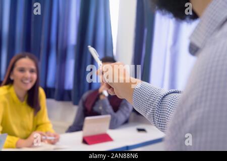 Cropped image of senior university professor pointing on something with pencil to the students. Explain lesson to the students and helping them to lea Stock Photo