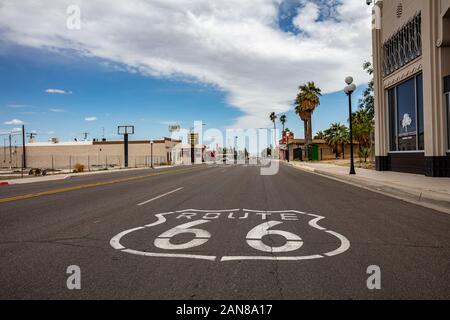 Needles, California, USA. May 26, 2019. Route 66 historic mother road sign on the asphalt street, empty road, cloudy blue sky background. Stock Photo