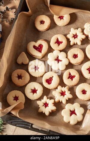 Linzer Christmas cookies filled with marmalade on parchment paper in a baking tray, top view Stock Photo