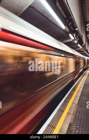 Motion blurred moving train on London Underground tube station Stock Photo