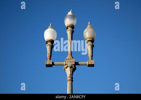 Ornate Triple Globe Vintage Street Lamp Against a Clear Blue Sky Stock Photo