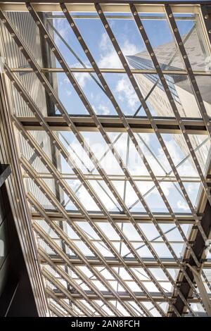 Glass roof. Blue cloudy sky through a metal construction with glass panels, View and natural light with protection from rain and sun. Vertical photo, Stock Photo