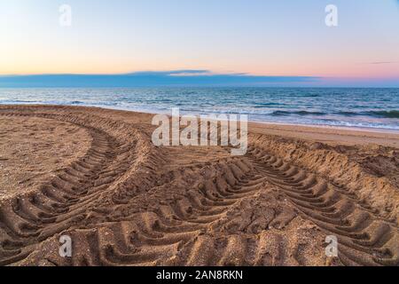 Tire tread marks on sand by sea Stock Photo