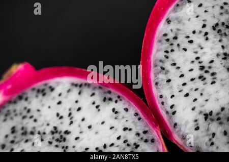 Dragon fruit. Vibrant Dragon Fruit on black background. Sliced white dragon fruit or pitaya on black plate on the table, close-up. Tropical and exotic Stock Photo