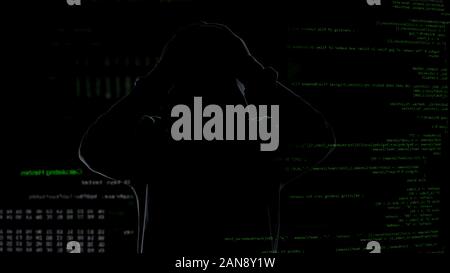 Hacker shadow touching head against codes background, unsuccessful attempt Stock Photo