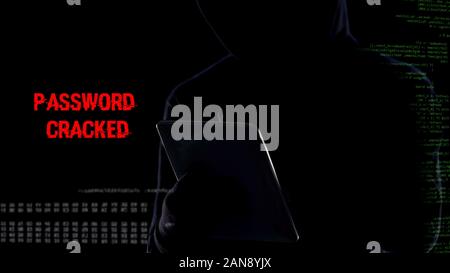 Male in hood typing on tablet, cracking password, gathering personal data Stock Photo