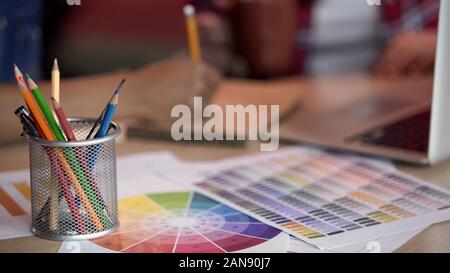 Female designers taking notes, colored pencils holder standing on color spectrum Stock Photo