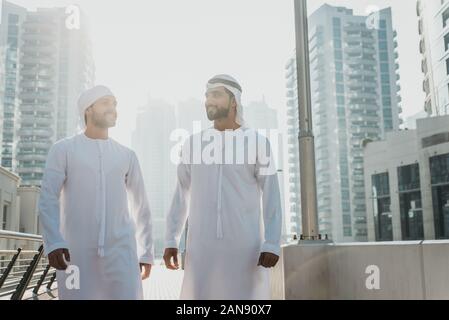 Two young businessmen going out in Dubai. Friends wearing the kandura traditional male outfit in Marina Stock Photo