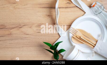 https://l450v.alamy.com/450v/2an92b8/eco-natural-paper-cups-and-plate-cotton-reusable-produce-bag-bamboo-cutlery-set-and-green-leaf-on-wooden-table-top-view-zero-waste-plastic-free-co-2an92b8.jpg