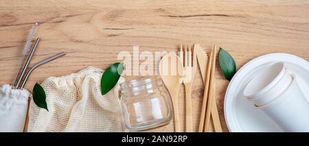 Bamboo utensils cutlery set, grocery mesh bag, glass jar, carton paper plate and cups, stainless steel drink straws on wooden background. Zero waste, Stock Photo