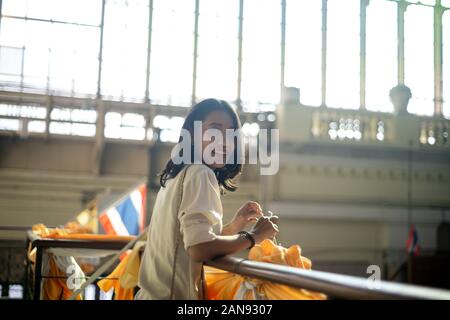 Black wavy hair woman in white shirt standing at the handrail of second floor in the train station while waiting for her travel train. Stock Photo