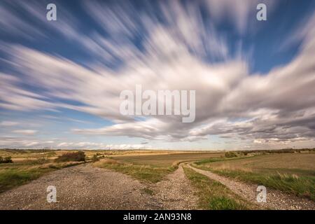 Rural region with two dirt roads and fast passing clouds Stock Photo