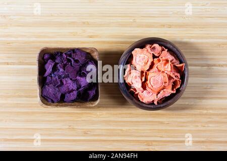 Dried carrot and beet chips in a wooden bowl on a cutting Board. Organic natural food. Top view, flat lay. Stock Photo