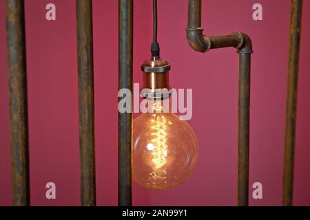 classic different retro light bulbs hanging on brick red background at night . Decorative antique edison style light bulbs against brick wall Stock Photo