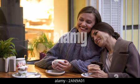 Two female friends having good time sitting in cafe, coffee and dessert on table Stock Photo