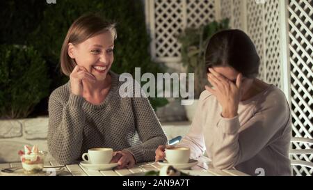 Joyful female friends discussing gossips, sitting cafe table laughing, leisure Stock Photo