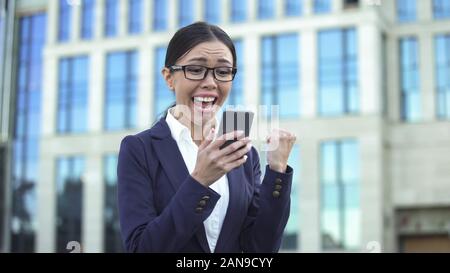 Excited lady in suit receiving good news, making yes-gesture, successful startup Stock Photo