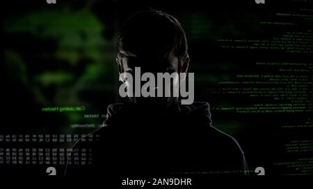 Young incognito man, internet hacker with numbers and code, cybercrime threat Stock Photo
