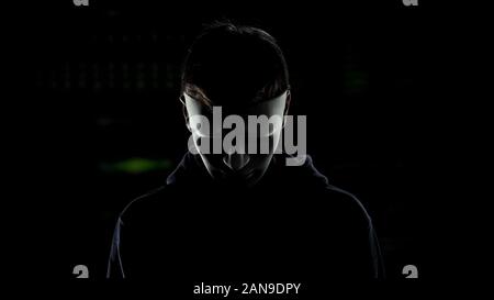 Man in scary mask isolated on dark background, serial killer hiding identity Stock Photo