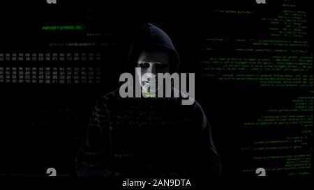 Hacker in white mask getting ready to work, attacking system with malware code Stock Photo