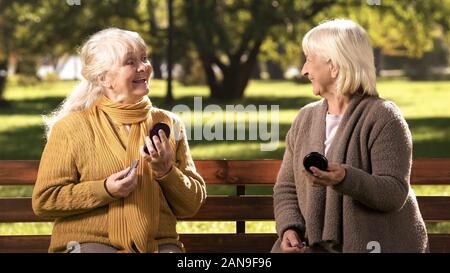 Funny mature women making-up lips and looking to each other, fashion for elder Stock Photo