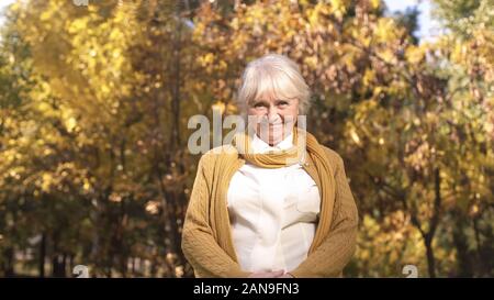 Attractive mature woman posing at camera on background of autumn weather Stock Photo