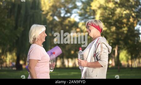 Two women friends meeting before workout in park and giving advices each other Stock Photo
