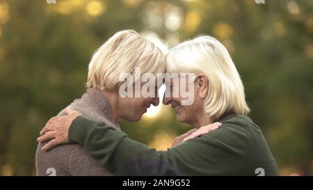 Two mature female friends tightly hugging each other and smiling, happy meeting Stock Photo