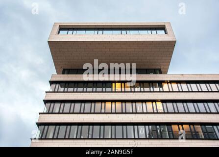 Architecture design of modern office building with balcony on the top, viewed from low angle against cloudy sky
