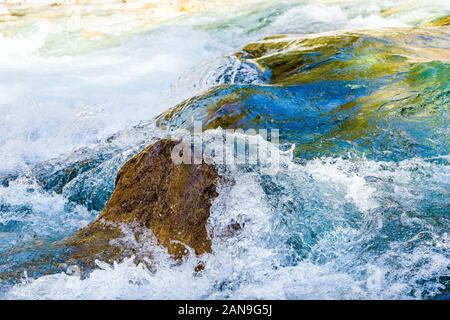 Clear mountain river water tumbling over boulders in the Nepal Himalayas Stock Photo