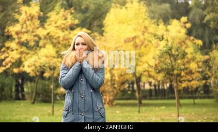 Freezing lady in stylish coat warming hands, waiting for boyfriend, autumn scene Stock Photo