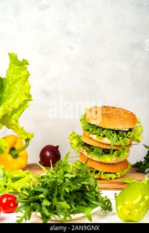 Tasty burger with cutlet, cheese and letuce on wooden board. Stock Photo