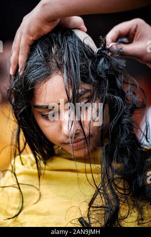 Batu Caves, Malaysia - January 21 2019 : Close-up of young lady devotee getting tonsured or head shaving ritual in Thaipusam Festival. Stock Photo