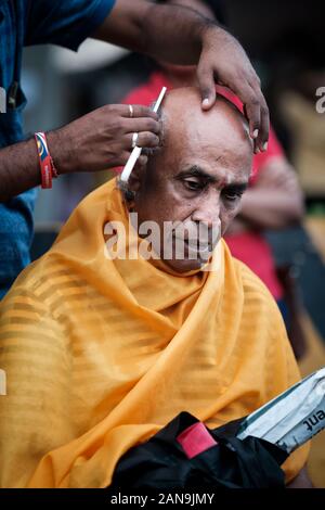 Batu Caves, Malaysia - January 21 2019 : Close-up of men devotee getting tonsured or head shaving ritual in Thaipusam Festival. Stock Photo
