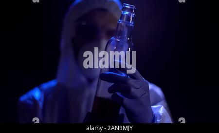 Criminologist holding glass bottle in hands, analyzing crime scene evidence Stock Photo