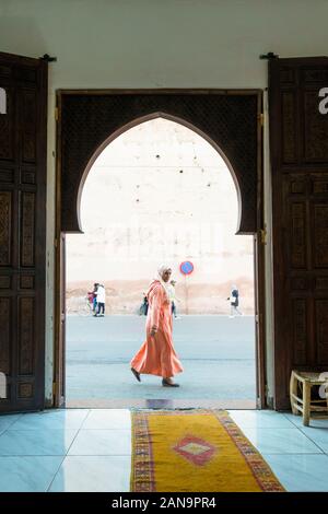 Marrakech, Morocco - January 7,2020:  Muslim woman walking on the street capture through arabic gate Stock Photo