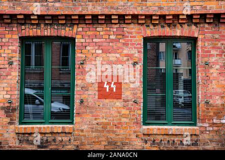 Old electricity sign painted on a wall between two windows Stock Photo