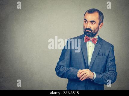 Businessman looks worried surprised, shocked, stunned to the side blank copy space. Mixed race bearded man, model isolated on gray studio wall backgro Stock Photo