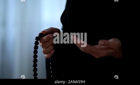 Muslim woman praying with islamic beads in hand, religious meditation, worship Stock Photo