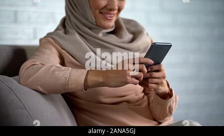 Smiling arab woman in hijab watching photos on smartphone, good memories Stock Photo