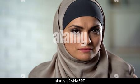 Depressed female in hijab looking sadly in camera, feeling hurt, abused woman Stock Photo